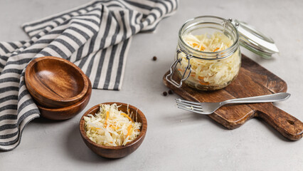 Sauerkraut with carrots in a wooden bowl and glass jar.