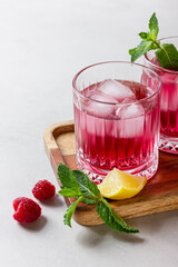 Raspberry cocktail with ice in a glass on a light background