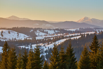 Winter sunset over a snowy mountain landscape with a rural village.