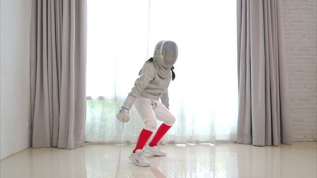 Before the tournament day, a boy dressed in fencing gear are rehearsing in gym