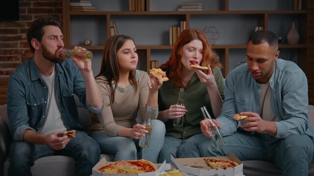 Diverse four friends conversation on couch home pizza party eating snacks delivery service multiracial people with beer resting at living room festive spending time women men drinking talking joyful