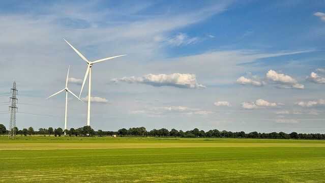 Landscape photo of two tall wind turbines in meadow farming field. Green renewable energy, global warming, climate change, sustainability, farm land concept. 