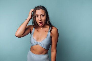 A surprised woman in a blue sports outfit against a blue background.