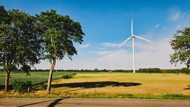 Tall white wind turbine in summer landscape on a warm day. Green energy generation for future technology. 