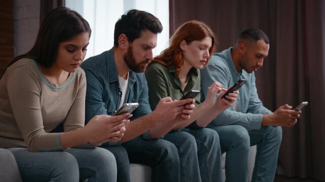 Millennial diverse four friends overusing mobile phones addicted gadgets at home party multiracial people men women sitting in line on couch using smartphones ignoring online apps scrolling problem