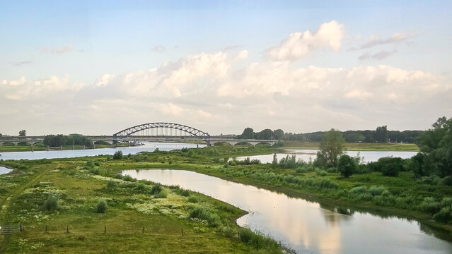 IJsselbrug bridge over IJssel river near Zwolle blue sky nature landscape farmland grass field.