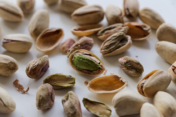 Peeled and whole pistachio nuts arranged together on clean white backdrop.