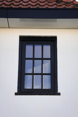 Black window in white wall under roof. House building European architecture build in neighborhood. 