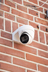 Security camera on brick wall, surveillance technology for safety and protection.