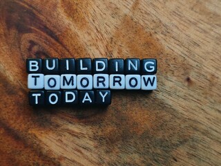 Building Tomorrow Today Letter Beads on Rustic Wood Surface Message of Progress.