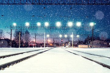 Winter night landscape, illuminated railway station by winter night under snowfall, concept of winter night travels on Christmas time