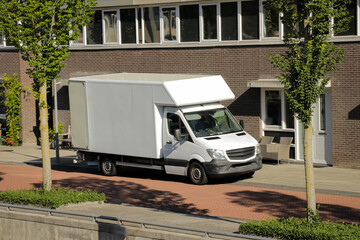 White moving truck in street. U haul car parked in Dutch, European neighborhood.
