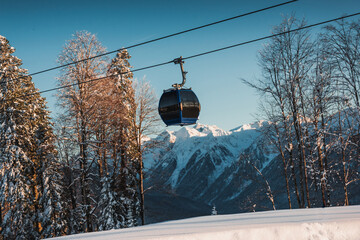 Gondola, cable car and ski lift with mountain, tree, blue sky on a sunny day at resort Krasnaya Polyana.