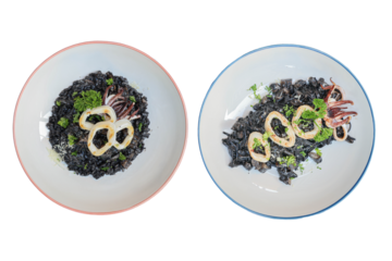 Black Squid Ink Risotto Plates: An overhead shot showcases two elegantly arranged plates of squid ink risotto, garnished with succulent squid rings and fresh herbs, a culinary masterpiece.
