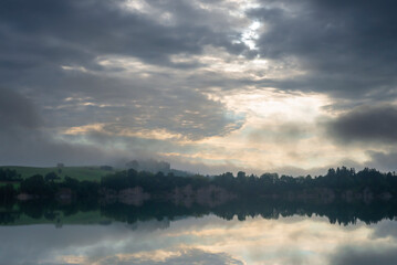 Nebelschwaden und Wolken ziehen bei Sonnenaufgang an der Illasschlucht über den Forggensee, Allgäu, Bayern, Deutschland