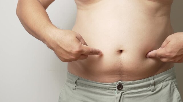 Closeup of Man Pinching Belly Fat &ndash; Weight Gain Concept