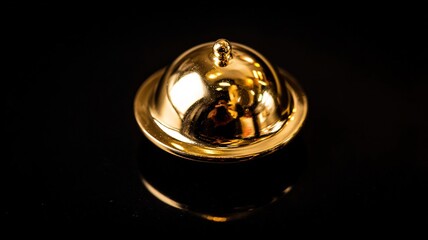 Polished Brass Christmas Bell with Matte Gold Plating and Tiny Clapper, Isolated on Dark Background with Sparkling Surface Reflections