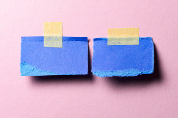 Pieces of blank blue paper memo reminder notes with adhesive tape and copy space for text on pink background