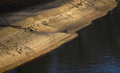 natural formation resembling a heart shape where a body of water meets a sandy or earthy bank. 