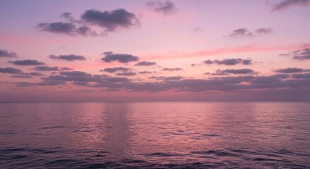 Obraz premium Gentle sunset over a tranquil ocean. Muted colors of pink and purple paint the sky and water