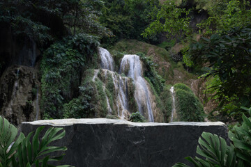 Stone table top podium with outdoor waterfall green tropical forest nature background landscape.Natural water mineral product present placement pedestal rock stand display.jungle paradise concept.