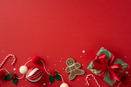 Vibrant Christmas scene featuring a gingerbread man, candy cane, holly and berries beside a green wrapped gift on a red background, ideal for holiday greeting and seasonal promo