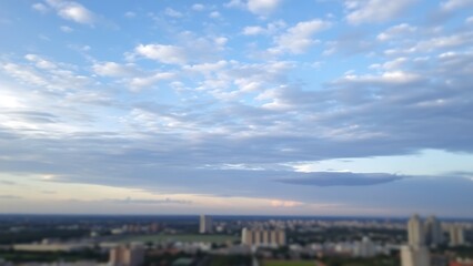 Obraz premium Panoramic sky view with soft clouds, subtly hinting at a blurred cityscape below.