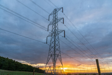 UK Electrical Pylon at sunset, high voltage Power lines part of a modern electricity infrastructure with a colourful sky