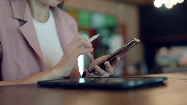 Modern smart office concept with businesswoman using stylus on tablet and checking smartwatch in colorful co-working space