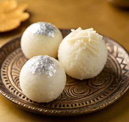 Three rasgulla sweets on a decorative plate, a traditional indian dessert