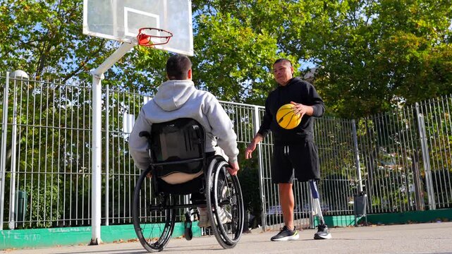 Disabled friends with wheelchair and prosthetic leg playing basketball together