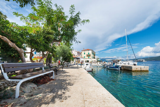 Sitzbank im Schatten unter B&auml;umen im Hafen von Valun auf der Insel Cres, Kvarner Bucht, Kroatien
