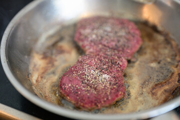 Frying pan with beef steak being cooked at home