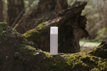 A dark and light glass serum bottle with a dropper, tree bark wood, moss. forest on a sunny day nature background. Concept of skin care, hydration, cosmetic demonstration eco-friendly product mock up