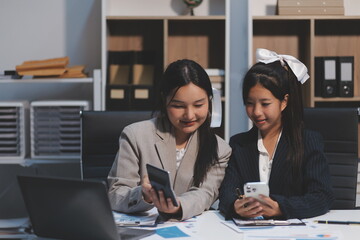 Two young Asian business woman talk, consult, discuss working with new startup project idea presentation analyze plan marketing and investment in the office.