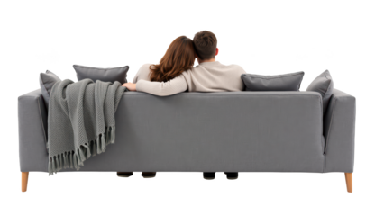 Cozy couple sitting on modern gray sofa, wrapped in soft blanket, enjoying moment together