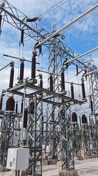 Cinematic pan right of high voltage electrical substation switchyard with current transformers and porcelain insulators against blue sky in energy industry.