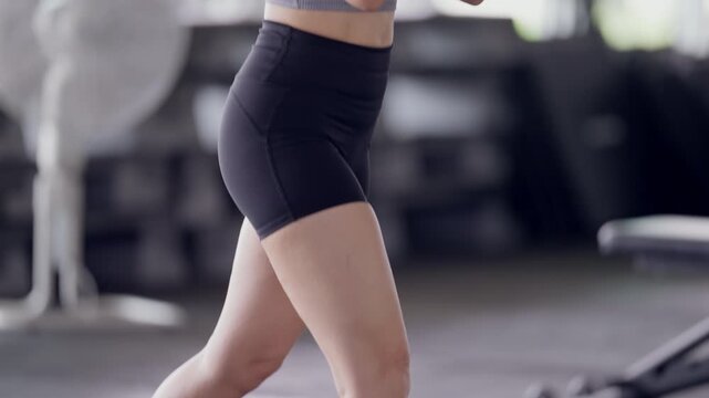 Confident Asian woman wearing workout gloves exercising at gym. Sweating and focused. Female fitness training, healthy lifestyle, strength and determination.