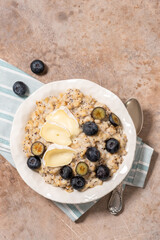 A bowl of oatmeal with blueberries, camembert cheese and poppy seeds