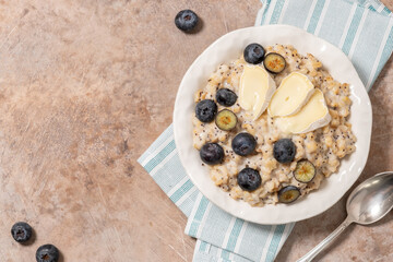 A bowl of oatmeal with blueberries, camembert cheese and poppy seeds