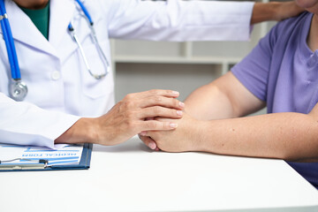 A male Asian doctor checks on an obese female patient at a desk, addressing her high blood...