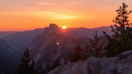 Obraz premium A breathtaking mountain vista bathed in the warm hues of a sunrise, featuring a soft focus on the distant peaks.