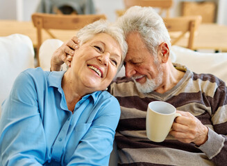 Portrait of a happy senior couple embracing talking and drinking coffee or tea at home