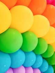 Background of colorful balloons with rainbow pattern, up close. Backdrop of bright color arrangement of latex balloons for decoration. Classic balloon type made from natural, biodegradable materials.