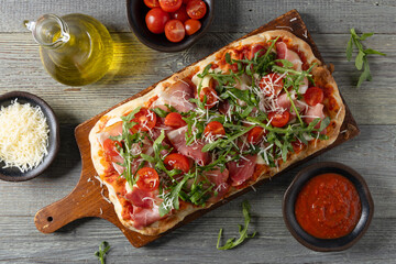 Traditional pinsa with Parma ham, fresh cherry tomatoes and arugula