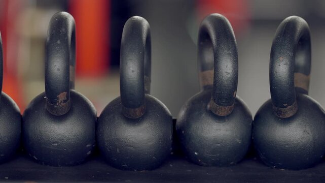 Macro shot of kettlebell handles with worn textures, placed in row on rack. Strength and fitness training equipment concept.