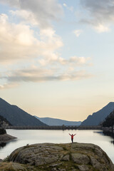 A man stands on a rock overlooking a body of water