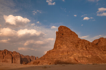 Late sunlight on red rocks against cloudscape near Al Ula in the desert of Saudi Arabia