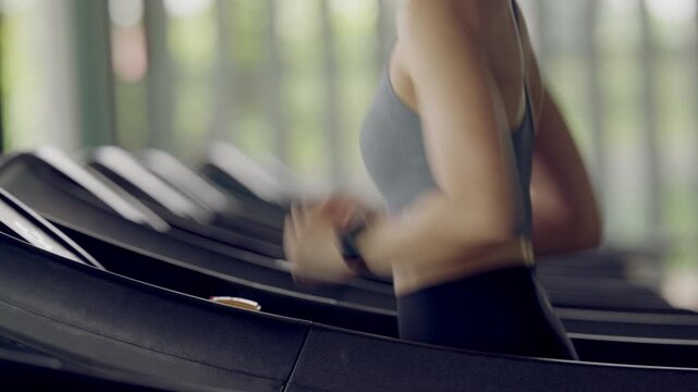 Woman begins her workout session by setting treadmill at gym. Focus, control, and commitment to health