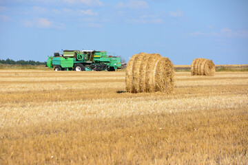 Obraz premium a wheat field with bales and combine harvester